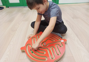 Chłopiec ćwiczy palce z wykorzystaniem labiryntu.